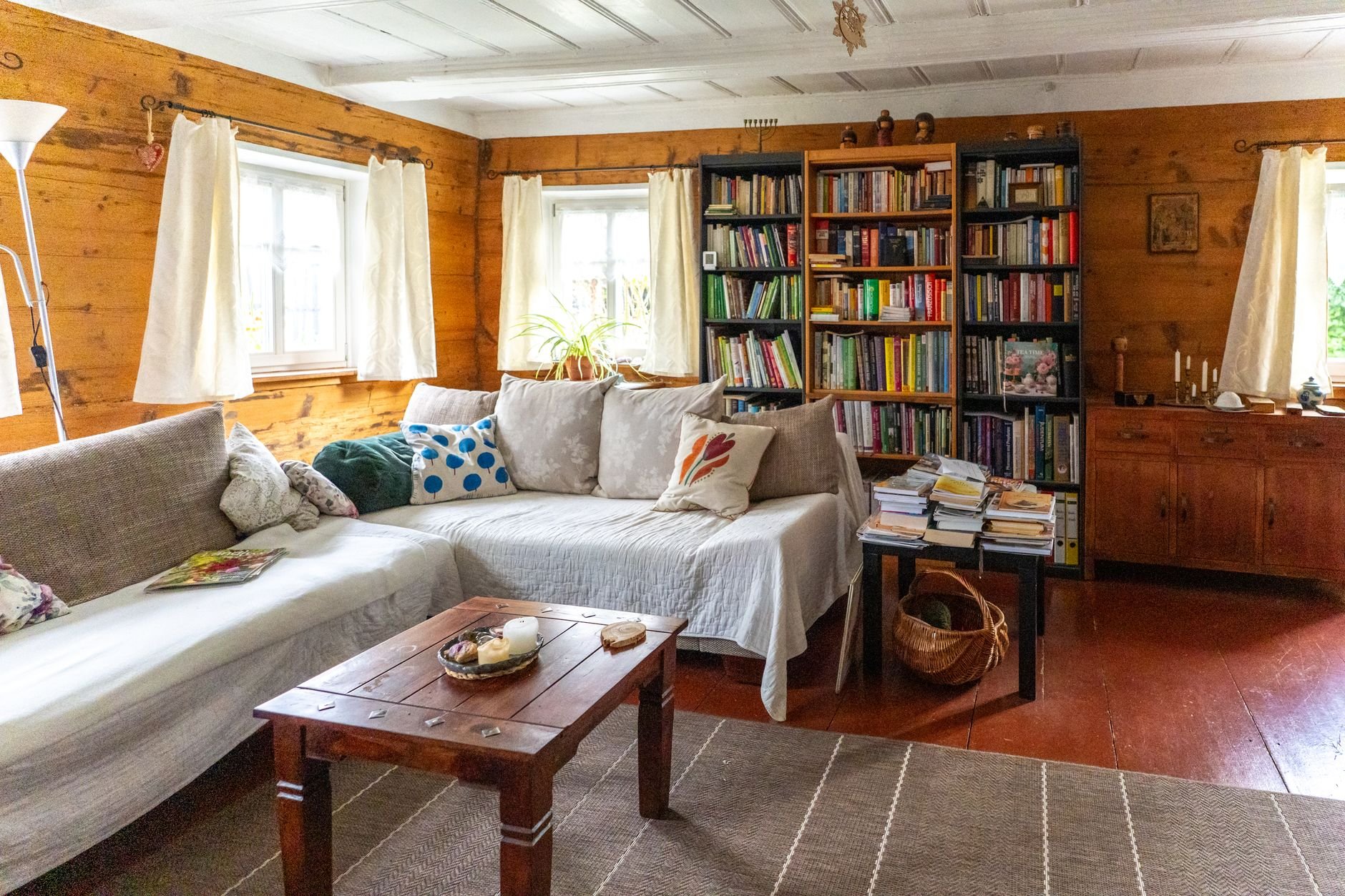 A rustic living room with bookshelves, cozy sofas, and warm lighting, creating a welcoming atmosphere.